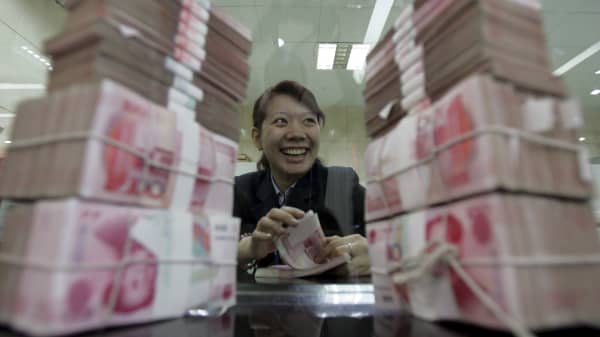 A clerk counts stacks of Chinese yuan at a bank in Beijing, China.