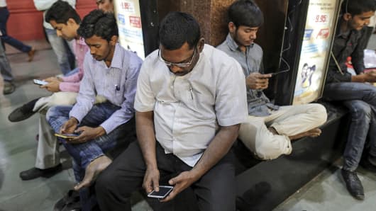 Passengers use their smartphones at Mumbai Central railway station in Mumbai, India, on January 22, 2016.