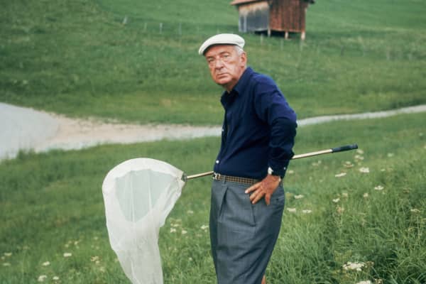 Portrait of Russian-born American writer Vladimir Nabokov (1899 - 1977) standing with a butterfly net outdoors in the hills of Switzerland.