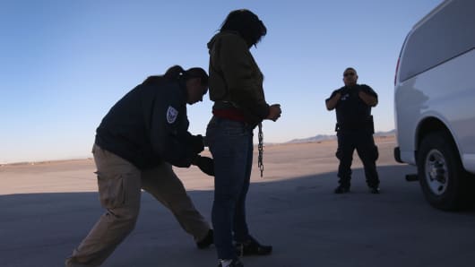 A security contractor frisks a detainee ahead of a deportation flight to Honduras.