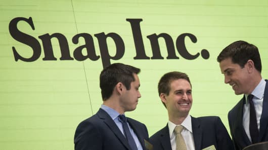 Snapchat co-founders Bobby Murphy, chief technology officer of Snap Inc., and Evan Spiegel, chief executive officer of Snap Inc., smile at each other after ringing the opening bell as Thomas Farley, president of the NYSE, looks on, March 2, 2017 in New York City.