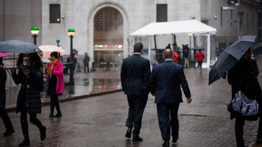 Pedestrians walk along Wall Street in front of the New York Stock Exchange.