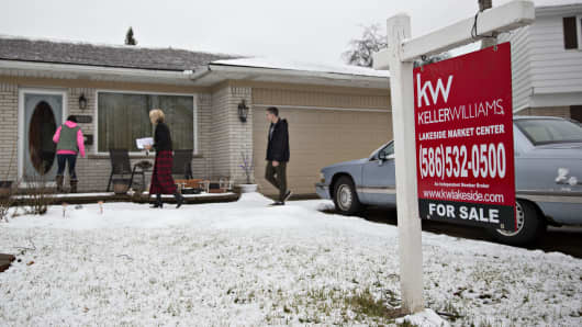 Prospective buyers and a real estate agent, center, enter a home for sale in Warren, Michigan.