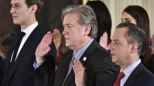 Senior Advisor to the President Jared Kushner, Counselor to the President Stephen Bannon and White House Chief of Staff Reince Priebus raise their hands during the swearing-in of senior staff in the East Room of the White House on January 22, 2017 in Washington.