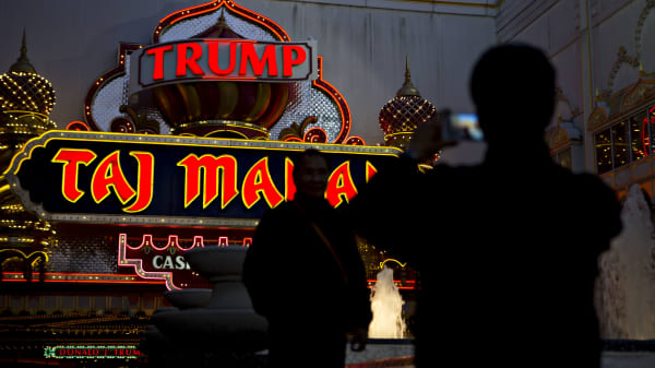 The silhouettes of visitors are seen taking photograph outside the Trump Taj Mahal casino and hotel, owned by Trump Entertainment Resorts Inc., in Atlantic City, New Jersey, U.S., on Sunday, May 8, 2016.