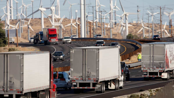 Emissions-producing diesel trucks and cars pass non-polluting windmills along the 10 freeway on December 8, 2009 near Banning, California.