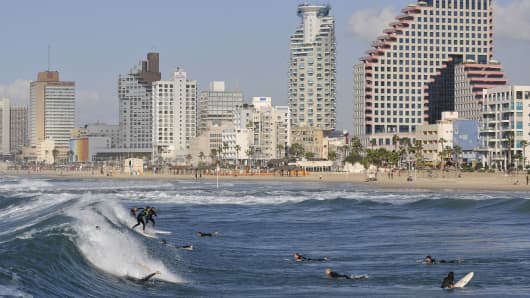 Surfers ride the waves on a beach in Tel Aviv, Israel
