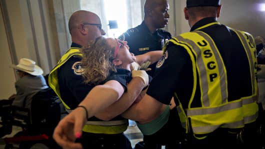 A demonstrator protesting cuts to Medicaid is carried away from the office of Senate Majority Leader Mitch McConnell by U.S. Capitol police officers at the Russell Senate Office building in Washington, D.C., U.S., on Thursday, June 22, 2