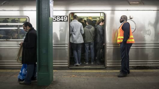 An MTA worker looks on as people stand on an idling train.