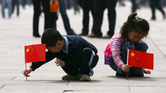 Children holding Chinese national flag play in Tiananmen Square in Beijing, China.