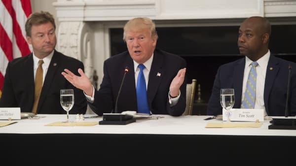 President Donald Trump speaks alongside US Senator Dean Heller (L), Republican of Nevada, and US Senator Tim Scott (R), Republican of South Carolina, during a meeting with Republican Senators to discuss the health care bill in the State Dining Room of the White House in Washington, DC, July 19, 2017.