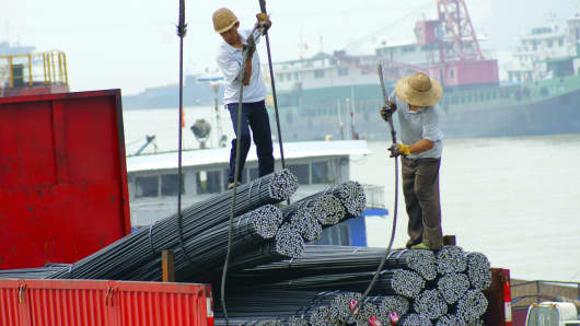 Two workers load steels products at a wharf in Yichang, China.