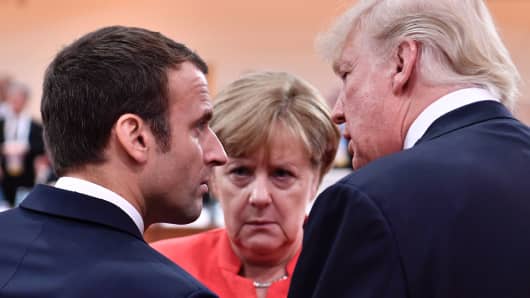 President Donald Trump (R), French President Emmanuel Macron (L) and German Chancellor Angela Merkel (C) chat at the start of the first working session of the G20 meeting in Hamburg, northern Germany, on July 7, 2017.