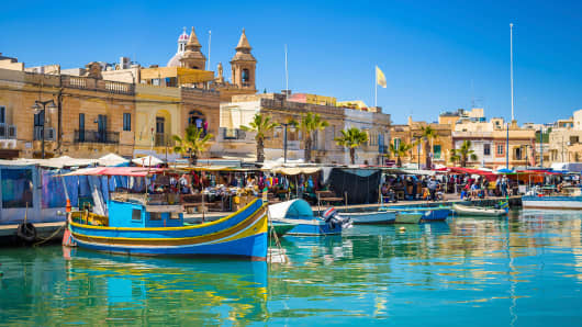 Marsaxlokk market with traditional Luzzu fishing boats in Malta.