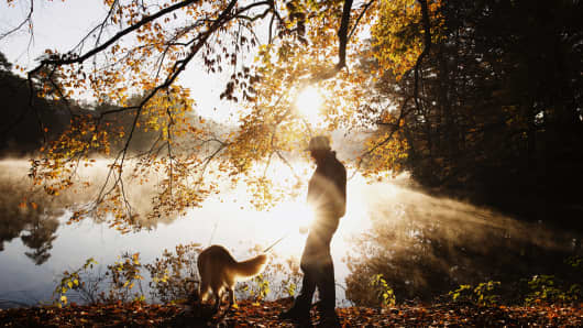 Silhouette of a man and his dog at sunrise.