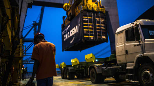 A worker waits as a shipping container is unloaded from the Hapag-Lloyd Holding AG Prague Express cargo ship onto a truck at the Cia Siderurgica Nacional SA (CSN) Sepetiba Tecon terminal inside the Port of Itaguai in Rio de Janeiro, Brazil.