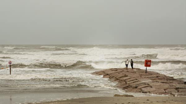 People stand on seawall by the Gulf of Mexico ahead of Hurricane Harvey in Galveston, Texas, U.S., on Friday, Aug. 25, 2017. Hurricane Harvey strengthened as it headed toward landfall in Texas, forecast to become the worst storm to strike the region in more than a decade.