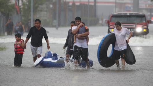 People walk down a flooded street as they evacuate their homes after the area was flooded from Hurricane Harvey on August 27, 2017 in Houston, Texas.