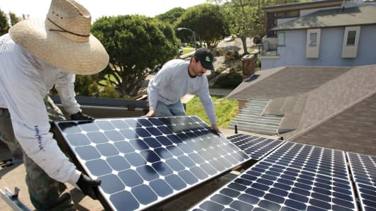 Workers install solar panels on a residential home in Santa Monica, Calif.