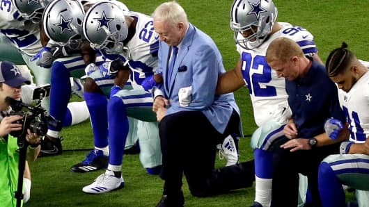 The Dallas Cowboys, led by owner Jerry Jones, center, take a knee prior to the national anthem prior to an NFL football game against the Arizona Cardinals, Monday, Sept. 25, 2017, in Glendale, Ariz.