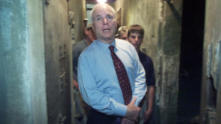 Vietnam war veteran and former Republican presidential frontrunner, Senator John McCain of Arizona steps down a dark corridor separating jail cells with his son Jack during a tour of the infamous "Hanoi Hilton" jail April 26 where he spent time as a prisoner of war.