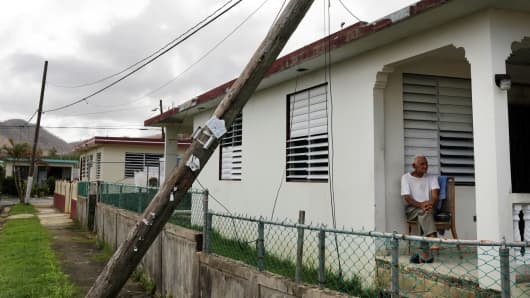A resident sits on his porch underneath a damaged power line as recovery efforts continue following Hurricane Maria in Ceiba, Puerto Rico, October 4, 2017.