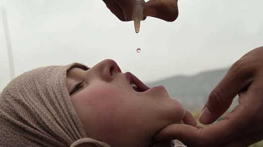 An Afghan health worker administers the polio vaccine to a child during a vaccination campaign in Kabul on February 28, 2017.