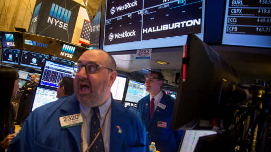Traders work beneath a monitor displaying Halliburton Co. signage on the floor of the New York Stock Exchange (NYSE) in New York, U.S., on Monday, May 2, 2016.