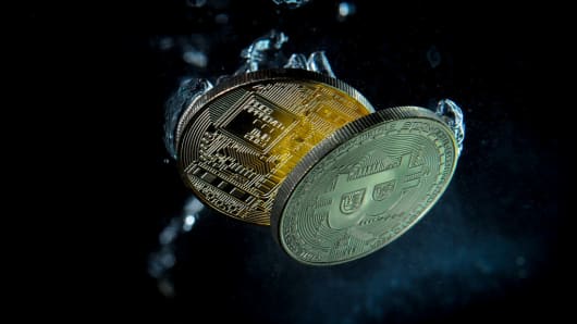 Bitcoin replica coins plunging in water.