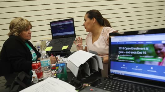 An insurance agent from Sunshine Life and Health Advisors, speaks with a customer as she shops for insurance under the Affordable Care Act at a store setup in the Mall of Americas in Miami, Florida.