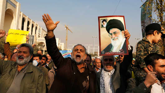 Pro-government demonstrators hold a poster of Iran's supreme leader Ayatollah Ali Khamenei during a march following the weekly Muslim Friday prayers in Tehran on January 5, 2018.