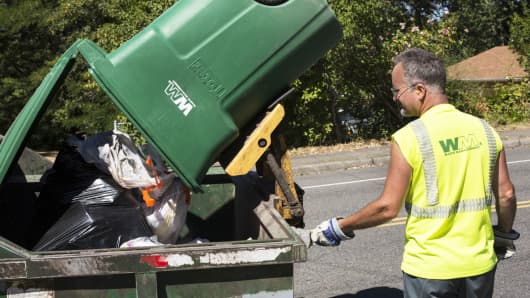 A worker empties garbage from a Waste Management trash bin in Seattle.