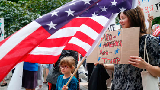 Protesters hold a placard reading 'Pro America - Anti-Trump'.
