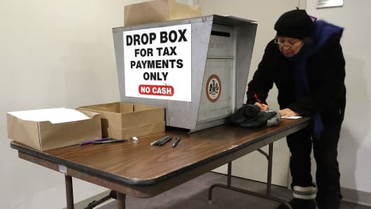 Residents fill out paper work and use locked drop boxes to pay their taxes at the Fairfax County Government Center December 28, 2017 in Fairfax, Virginia.