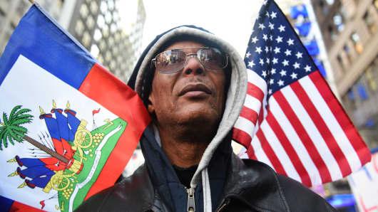 Protestor Pierre Gabriel from Haiti carries flags during a march on Martin Luther King Jr. Day in Times Square, called Rally Against Racism: Stand Up for Haiti and Africa in New York January 15, 2018.