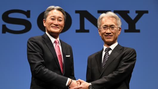 Sony president and CEO Kazuo Hirai (L) shakes hands with executive deputy president and CFO, Kenichiro Yoshida (R), during a press briefing at the company's headquarters in Tokyo on February 2, 2018. Sony chief executive Kazuo Hirai, who led a major and successful overhaul at the Japanese electronics giant, will step down at the end of March, the firm said on February 2 and will become Sony chairman.