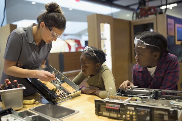 Scientist teaching twin sisters assembling electronics in science center