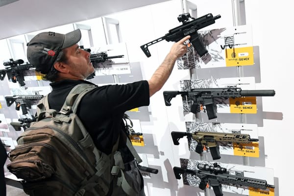 A convention attendee looks at rifles displayed at the Sig Sauer booth at the 2018 National Shooting Sports Foundation's Shooting, Hunting, Outdoor Trade (SHOT) Show at the Sands Expo and Convention Center on Jan. 23, 2018 in Las Vegas.
