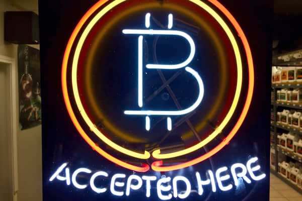In this Feb. 7, 2018, photo, a neon sign hanging in the window of Healthy Harvest Indoor Gardening in Hillsboro, Ore., shows that the business accepts bitcoin as payment.