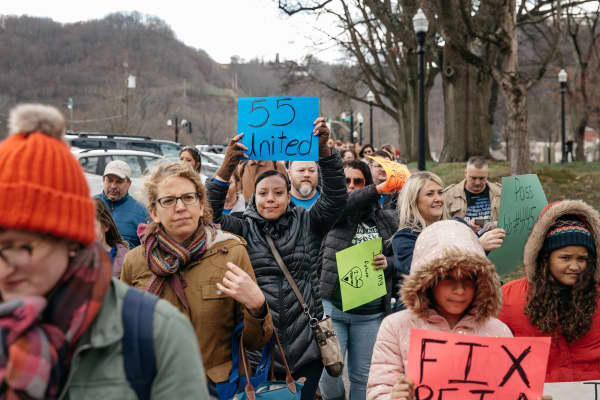Teachers and demonstrators hold signs during a rally outside the West Virginia Capitol in Charleston, West Virginia, on Friday, March 2, 2018.