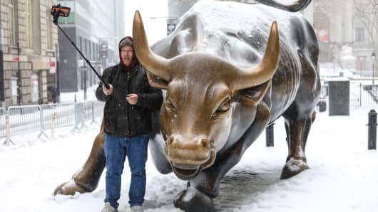 A man takes a selfie with Wall Street's famous Charging Bull during a snowstorm in New York City.
