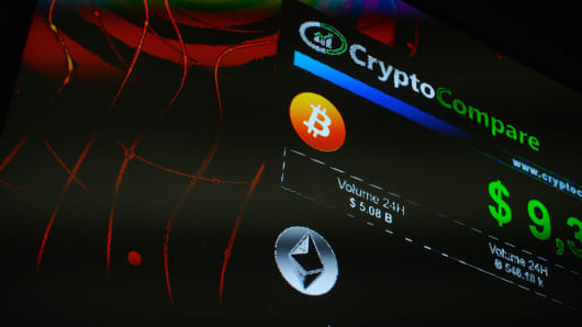 The symbols of Bitcoin and Ethereum cryptocurrencies sit displayed on a screen during the Crypto Investor Show.