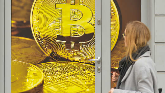 A lady passes in front of a Bitcoin exchange shop 