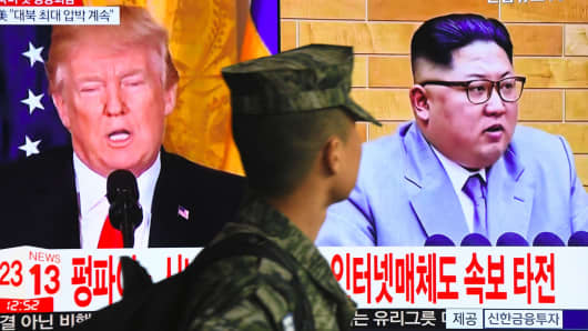 A South Korean soldier walks past a television screen showing pictures of US President Donald Trump (L) and North Korean leader Kim Jong Un at a railway station in Seoul on March 9, 2018.