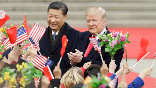 Chinese President Xi Jinping and President Donald Trump greet attendees waving American and Chinese national flags during a welcome ceremony outside the Great Hall of the People in Beijing, China, on Nov. 9, 2017.