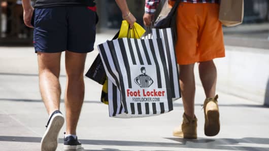 Customers walk with Foot Locker shopping bags on the Third Street Promenade in Santa Monica, California.