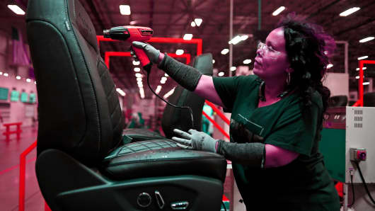 A worker uses a heat gun to smooth out the wrinkles on a car seat during production at the Lear Corp. manufacturing facility in Hammond, Indiana.