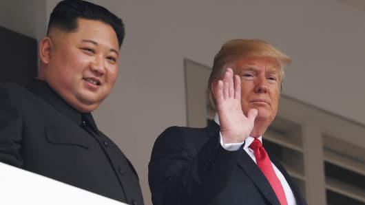 President Donald Trump (R) waves as he and North Korea's leader Kim Jong Un look on from a veranda during their historic US-North Korea summit, at the Capella Hotel on Sentosa island in Singapore on June 12, 2018.