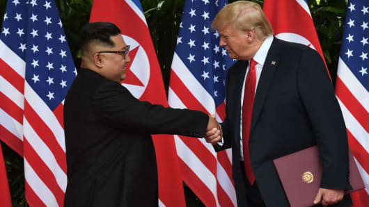 North Korea's leader Kim Jong Un (L) shakes hands with US President Donald Trump (R) after taking part in a signing ceremony at the end of their historic US-North Korea summit, at the Capella Hotel on Sentosa island in Singapore on June 12, 2018.