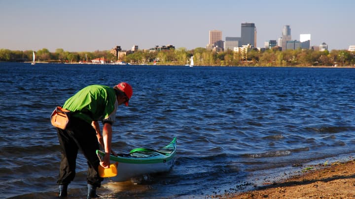 A man places his kayak in Lake Calhoun on a warm spring day in , Minneapolis, Minnesota
